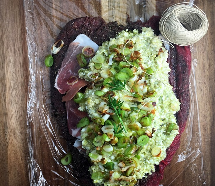 1. Этап. Лосятина в духовке: В небольшой миске смешайте мягкий творог с песто из базилика и вареным киноа. Нагрейте сковороду на среднем огне, растопите 1 ст.л. сливочного масла, добавьте нарезанный лук-порей, измельченный чеснок и обжарьте до золотистого цвета. Разложите подготовленный пласт из лосятины, положите тонкие ломтики ветчины, творожную смесь и сверху лук-порей с чесноком.