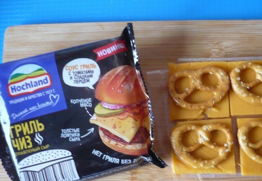 1. Этап. Крендели, запеченные с плавленым сыром Хохланд: Каждый ломтик плавленого сыра Гриль Чиз разрежьте на четыре части и сверху положите по крендельку.