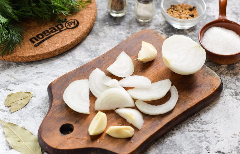 1. Этап. Огурчики по-болгарски на зиму: Очистите лук и чеснок, нарежьте лук полукольцами.