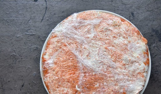 1. Этап. Салат Приручить дракона 2024: Поверх бананов распределяю слой грецких орехов и оставшуюся морковь с изюмом. Накрываю салат свободными краями пищевой пленки и ставлю в холодильник для пропитывания.