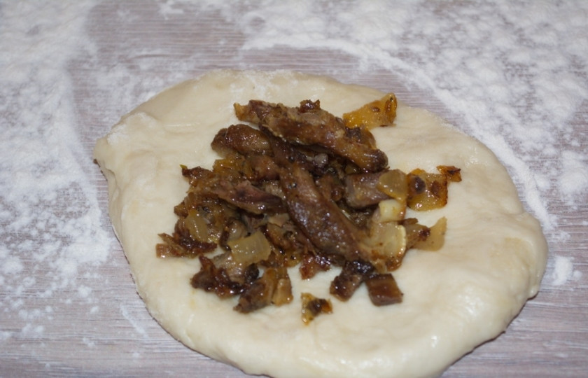 1. Этап. Булочки с мясом в духовке: Выложите в центр каждой лепешки мясную начинку. Соберите края, хорошо защипните их.