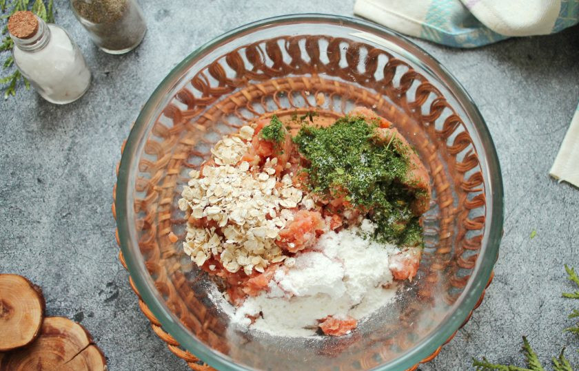 1. Этап. Постные котлеты из горбуши: В миску выложите фарш горбуши, добавьте крахмал, овсяные хлопья и сушеную зелень.