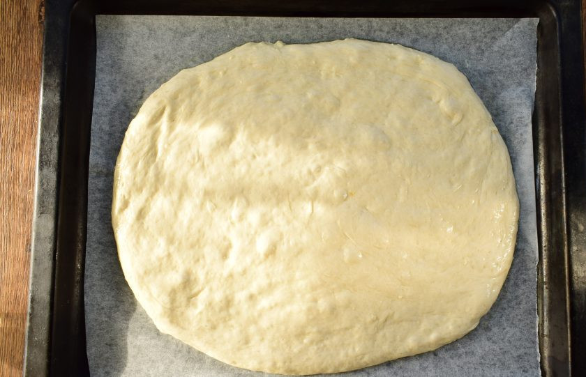 1. Этап. Матнакаш на кефире: Противень застелите пергаментом для выпечки. Выложите тесто, разровняйте в виде лепешки, дайте постоять в течение 15 минут.