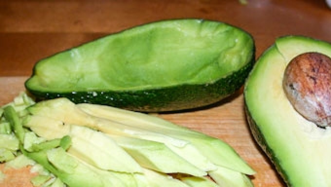 1. Этап. Салат из авокадо и креветок в лодочках: Авокадо разрежьте на 2 половинки. Аккуратно выньте косточку. При помощи ложки или ножа, аккуратно, чтобы не повредить кожицу, выньте мякоть авокадо, нарежьте ее кубиками.