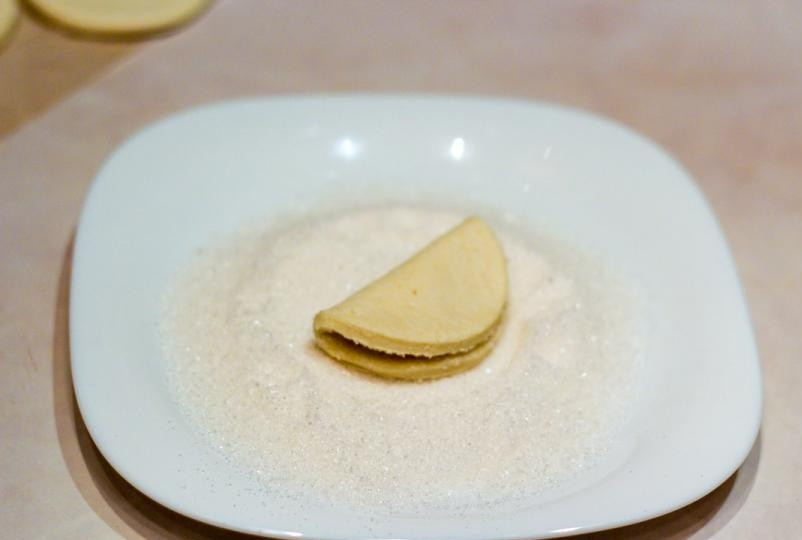 1. Этап. Творожное печенье Ушки: Сложите круг пополам, сахарной стороной внутрь. Тесто немного придавите.