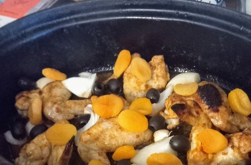 1. Этап. Курица, запеченная с хариссой и курагой: Вынуть из духовки. В ёмкость добавить луковые конусы, чеснок, абрикосы и оливки. Отправить в духовку ещё на 20 минут.