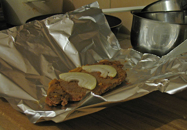 1. Этап. Ромштекс из свинины в духовке: Обжарили мясо на разогретой сковороде в масле. Добавили немного воды, горчицу и соус. Затем выложили в фольгу, сверху положили пару колец лука.