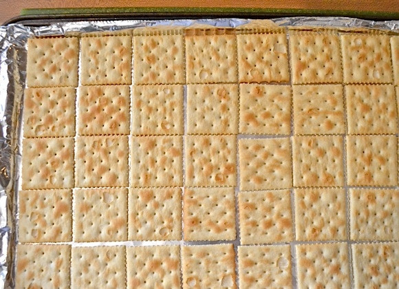 1. Этап. Десерт из крекеров с шоколадом: 1. Сначала застелите противень фольгой, сформировав небольшие бортики. Выложите соленые крекеры в один слой.