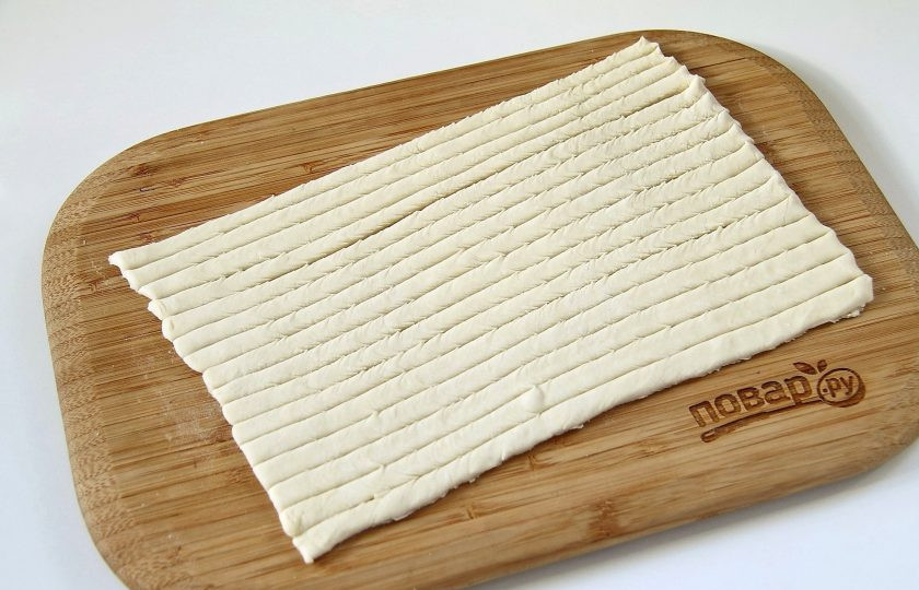 1. Этап. Мясные шарики в слоеном тесте: Раскатайте каждый пласт слоеного теста в прямоугольник, толщиной около 3 мм и разрежьте на полоски шириной 5-7 мм.