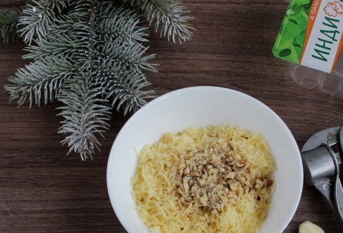 1. Этап. Закуска Ёлочные шары: Смешайте в чашке сыр, орехи, филе индейки. Выдавите через пресс зубчик чеснока.