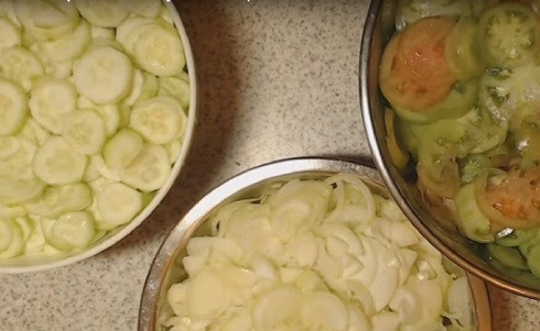 1. Этап. Салат из помидор и огурцов на зиму: Вымоем овощи и нарежем их в разные емкости. Огурцы можно очистить от кожуры, а можно оставить и так. Добавим в нарезанный лук чайную ложку соли, а оставшуюся распределим пополам между огурцами и помидорами. Перемешаем овощи с солью и оставим часов на 5-6, можно на ночь.