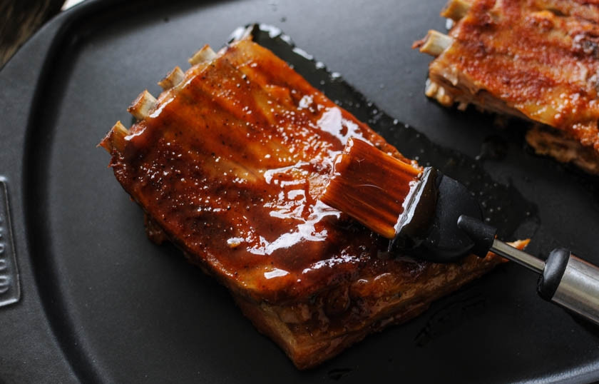 1. Этап. Свиные ребра барбекю: Разогрейте гриль. Рёбра достаньте из духовки и слегка остудите. Затем обильно обмажьте их соусом барбекю. Уже можно обжаривать рёбра на гриле. С каждой стороны обжаривайте их по 3-4 минуты.