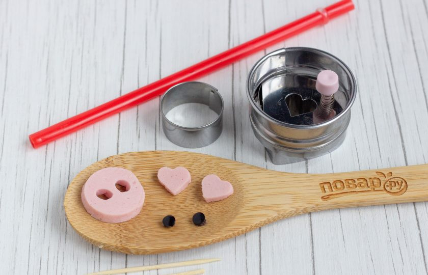 1. Этап. Закуска в тарталетках Поросята: Сделайте заготовки для поросят. Из маслин трубочкой выдавите глазки. Небольшие сердечки из колбасы будут ушками, а в круге из колбасы сделайте 2 дырочки трубочкой, получится пяточок.