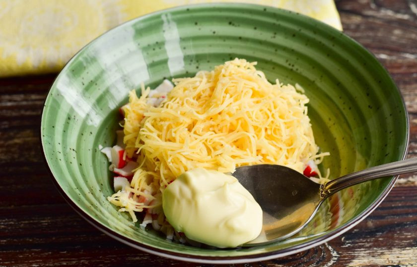 1. Этап. Крабовый салат как в Крошке-картошке: Выложите крабовые палочки и сыр в миску. Добавьте майонез.