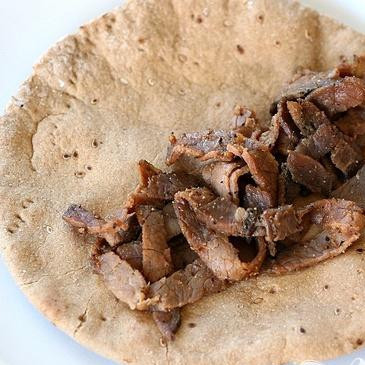 1. Этап. Гирос с говядиной и овощным соусом: 4. Сбрызнуть лепешки растительным маслом и разогреть в духовке или на гриле, пока они не станут мягкими. Заполнить лепешки начинкой из говядины, затем полить приготовленным соусом Дзадзики.