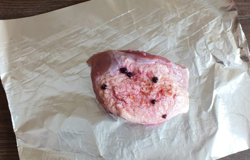 1. Этап. Буженина с клюквой: Возьмите фольгу. Выложите на нее подготовленную свинину. Заверните так, чтобы место соединения краёв фольги было наверху.