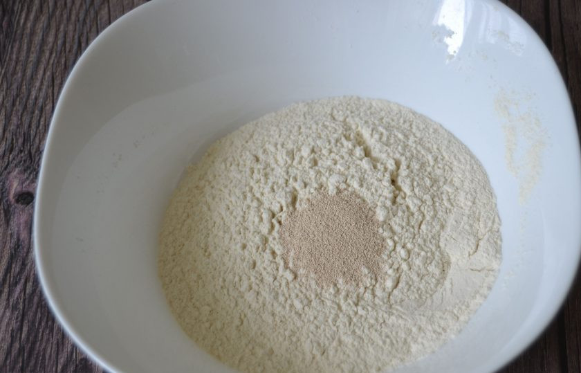 1. Этап. Воскресный пирог: Всыпьте в муку сухие дрожжи.