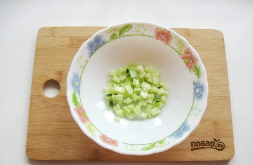 1. Этап. Салат с курицей, зеленым горошком и огурцом: Огурец помойте и мелко нарежьте. Если у огурца толстая кожура, то можно его очистить.
