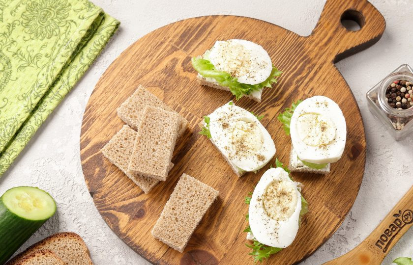 1. Этап. Канапе со шпротами и огурцом: Яйца очистите и нарежьте кружочками, выложите на салат. Посолите и поперчите по вкусу.