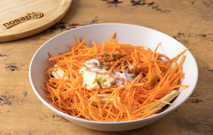 1. Этап. Соевая спаржа с морковью по-корейски: Морковь очистите и натрите на тёрке для моркови по-корейски. Чеснок мелко измельчите. Добавьте соль, сахар, приправу для моркови по-корейски и глутамат натрия. Влейте уксус.