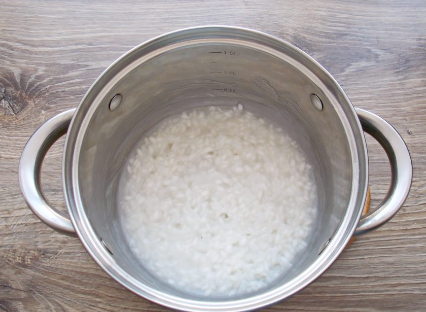1. Этап. Рисовая каша на сгущенном молоке: Рис хорошенько промойте и выложите в кастрюлю. Влейте холодную воду и поставьте на средний огонь. Доведите до кипения, и уменьшите огонь. Варите в течение 7-10 минут перемешивая. Каша должна дойти до полуготовности.
