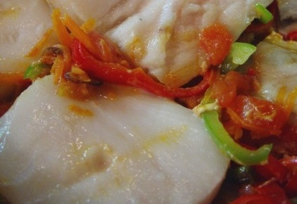 1. Этап. Масляная рыба, тушенная с овощами: 6. Выложите рыбу, сверху — кружочки помидоров. Влейте немного горячей воды, накройте крышкой и оставьте тушиться минут на 15.