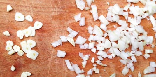 1. Этап. Жареные куриные сердечки со сметаной: Почистите лук и чеснок, мелко нарежьте.