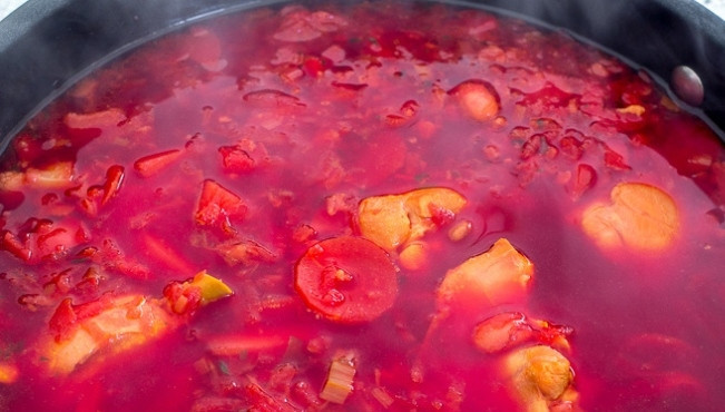 1. Этап. Свекольный суп на курице: Затем натрите в кастрюлю очищенную свеклу. Обжарьте продукты в течение 5 минут. Также нарежьте морковь кружками. Потом влейте бульон. Доведите его до кипения и всыпьте мелко нарезанный чеснок с чили.