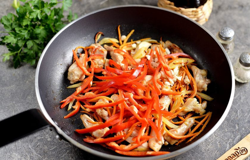 1. Этап. Лапша по-корейски с курицей: Болгарский перец почистите от семечек и плодоножки, нарежьте мякоть тонкой соломкой, всыпьте в сковороду. Тушите минуты 3, пока перец не станет мягким.