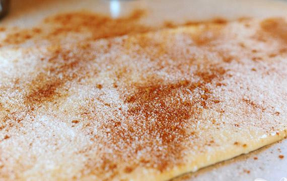 1. Этап. Мини-булочки с орехами: 3. Раскатать тесто в прямоугольник 20Х75 см. Залить сливочным маслом, затем равномерно посыпать сахаром и корицей равномерно по поверхности.