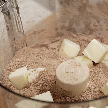 1. Этап. Шоколадные коржики с кремом и клубникой: 2. Добавить нарезанное на кусочки сливочное масло и перемешать, пока смесь не будет напоминать крошки.