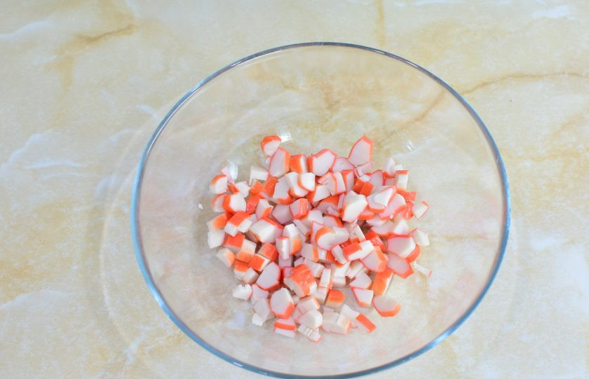 1. Этап. Крабовый салат с помидорами и огурцами: Крабовые палочки очистите от упаковки и нарежьте. Выложите их в миску.