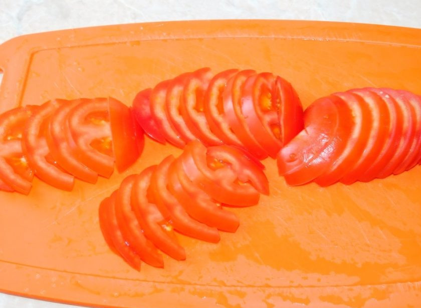 1. Этап. Свиные отбивные с овощами под сыром в духовке: Выложите нарезанные помидоры.