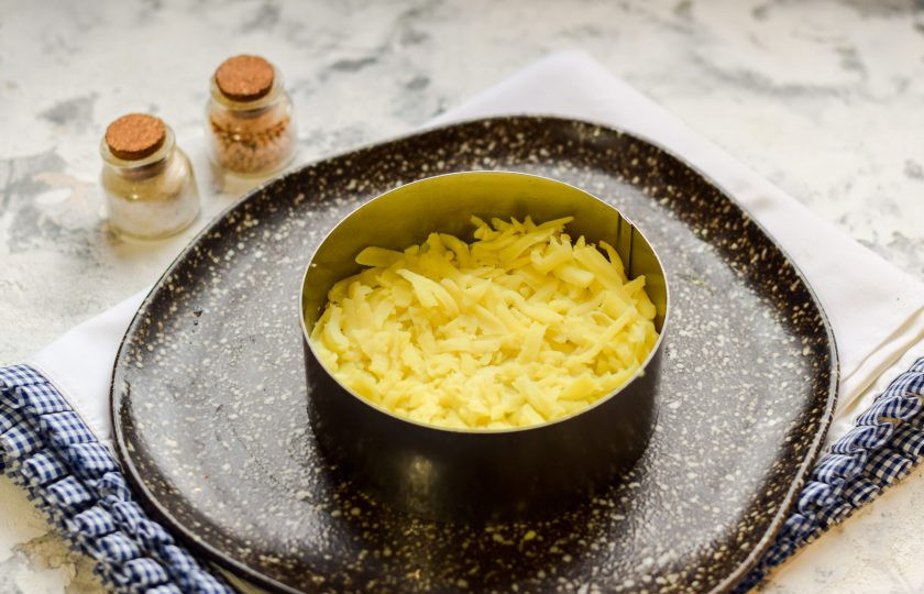 1. Этап. Салат Зимняя ночь: Картофель остудите и очистите, натрите на средней терке и выложите в салат первым слоем.