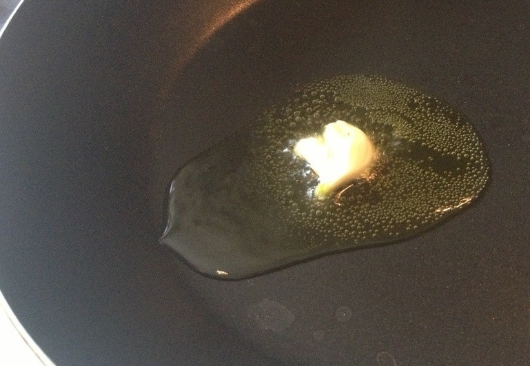 1. Этап. Салат Цезарь как в ресторане: В сковороду налить несколько ложек оливкового масла и бросить раздавленный зубчик чеснока.