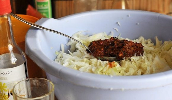 1. Этап. Кимчи из белокочанной капусты: Переложите капусту в большую миску, слегка ее присолите. Помните капусту руками, чтобы она пустила сок. Затем добавьте в нее острую аджику, сахар и влейте уксус.