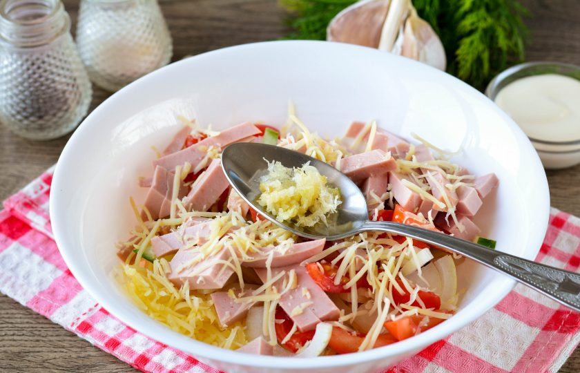 1. Этап. Салат Бахор с колбасой: Выдавите в салат чеснок, используя чесночницу.