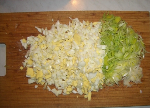 1. Этап. Салат с креветками и кальмаром: Яйца необходимо отварить, остудить и затем нарезать мелкими кусочками. А лук-порей нарезаем тонкими полосками.