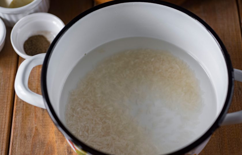 1. Этап. Картофель, фаршированный с рисом: Рис промойте, выложите в кастрюльку с водой и отварите до полуготовности 10-15 минут с момента закипания жидкости. Затем слейте воду с риса.