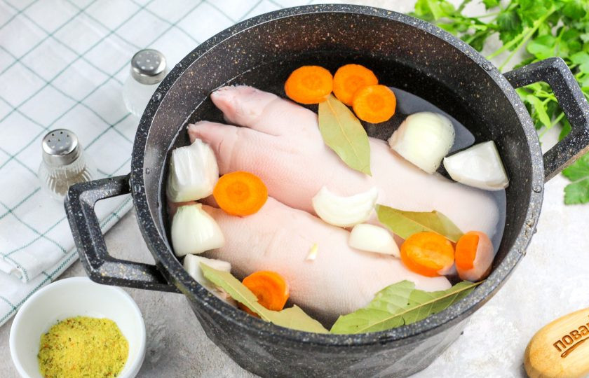 1. Этап. Желе из мясного бульона: Залейте горячую воду и поместите емкость на плиту. Доведите жидкость до кипения и проварите 10-15 минут, затем снимите пену шумовкой. Убавьте нагрев и томите мясо в бульоне примерно 1,5 часа, прикрыв емкость крышкой.