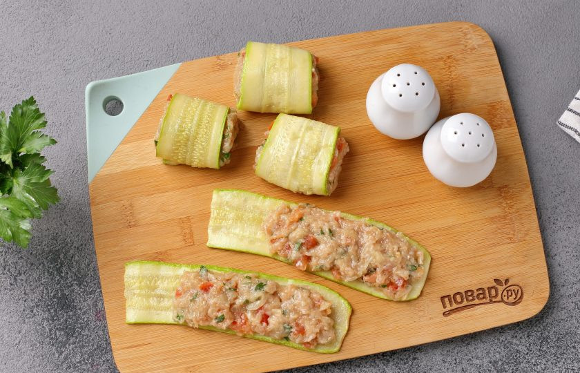 1. Этап. Рулетики из кабачков с мясом: Отступив от одного края, выложите на каждую полоску кабачка мясной фарш. Затем сверните кабачок с фаршем рулетиком.