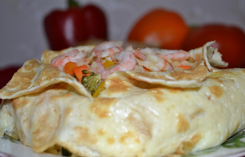 1. Этап. рис с овощами и морепродуктами: Перевернуть миску с содержимым на тарелку. Надрезать сверху крестообразно, отогнуть кончики омлета или блина. Сверху на рис положить креветки.