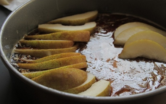 1. Этап. Грушевый шоколадный пирог: 4. Вымойте, обсушите и нарежьте тонкими дольками груши. На дно жаропрочной формы выложите карамель и распределите ровным слоем фрукты. Выкладывайте грушу красиво по кругу.