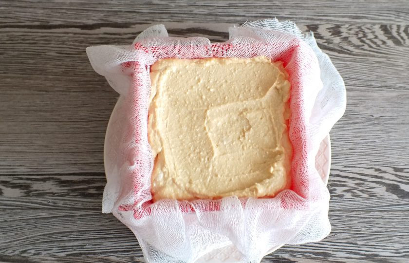 1. Этап. Пасха с вареной сгущенкой: Пасочницу застелите чистой марлей так, чтобы ее концы свисали. Выложите в нее творожную массу. Слегка стукните пасочницей, чтобы масса утрамбовалась.