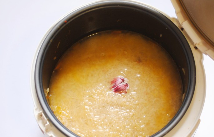 1. Этап. Баранина с рисом в мультиварке: Затем мы тщательно промываем рис в нескольких водах и выкладываем его ровным слоем на мясо с луком и морковью. Далее мы очень аккуратно наливаем в чашу воду так, чтобы она поднималась над рисом на 1-1,5 см, в центр риса закапываем пол головки чеснока. Теперь закрываем крышку мультиварки и устанавливаем режим 