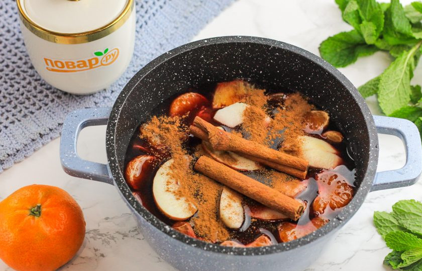 1. Этап. Черный глинтвейн: Промойте яблоко и разрежьте на четыре части, вырежьте семенные блоки. Промойте и нарежьте дольками. Добавьте вместе с лавровым листом, гвоздикой, корицей в емкость.