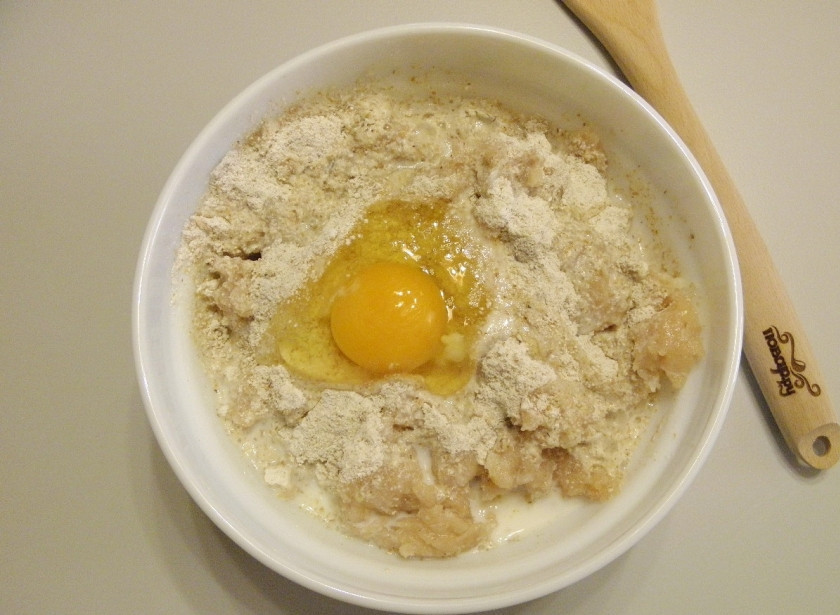 1. Этап. Котлетки из куриных грудок: Возьмите глубокую посудину и сложите фарш, добавьте яйцо, молоко и перемолотые хлопья. Перемешайте и оставьте фарш на 15-20 минут.