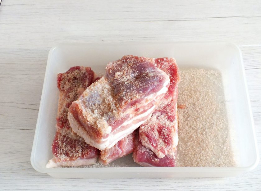 1. Этап. Засолка сала для копчения: Возьмите просторный лоток с крышкой. Сало нарежьте на куски, чтобы они свободно помещались в этот лоток. Дно присыпьте тонким слоем посолочной смеси. Каждый кусок сала тщательно натрите солью с перцем.