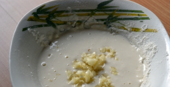 1. Этап. Жареные кабачки в кляре с сыром: Клярную смесь разведите с водой и добавьте измельченный чеснок. Перемешайте.