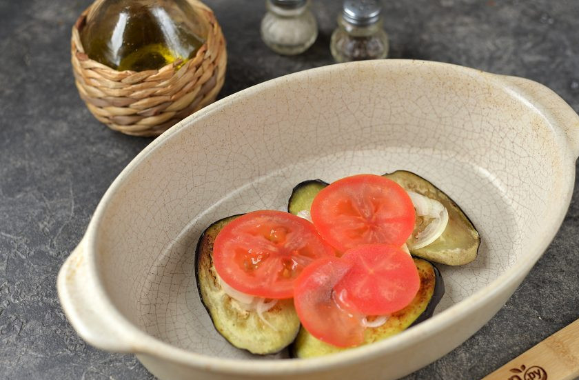 1. Этап. Форель с баклажанами в духовке: Подготовьте форму для запекания, выложите на дно несколько ломтиков баклажана, немного тонко нарезанного репчатого лука и тонко нарезанный помидор. Это будет так называемая 